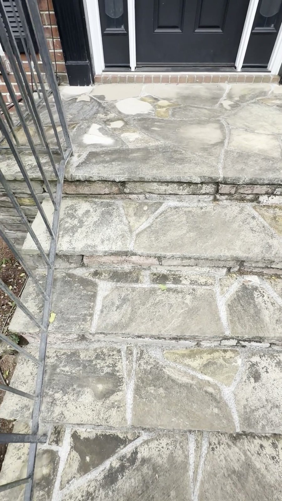 Flagstone entry steps before pressure washing, dark with grime